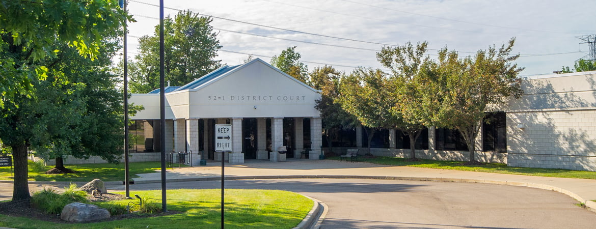 Front entrance of the 1st Division of the 52nd District Court in Novi. It's a small white colored courthouse building with several pillars.