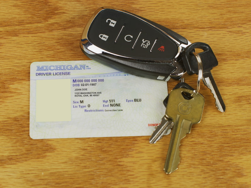 A drivers license and car keys are left sitting on a wood desk symbolizing drivers license restoration