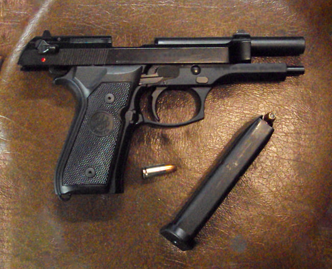 A Beretta M9 semi-automatic firearm is shown locked open with its magazine filled with hollow point speer gold dot ammunition