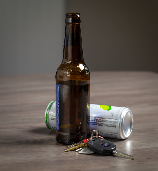 Drivers keys on a table next to empty alcohol containers symbolizing a DUI or OWI