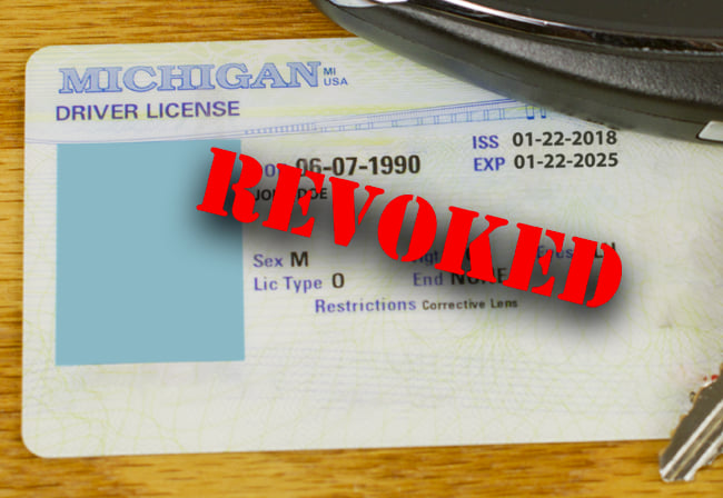 Michigan drivers license with red letters over it indicating the license has been suspended due to a felony dui or other drunk driving offense