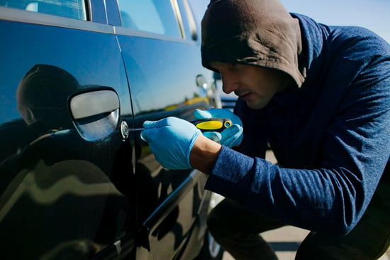 A shady person trying to lockpick a car indicating the theft crimes practice area