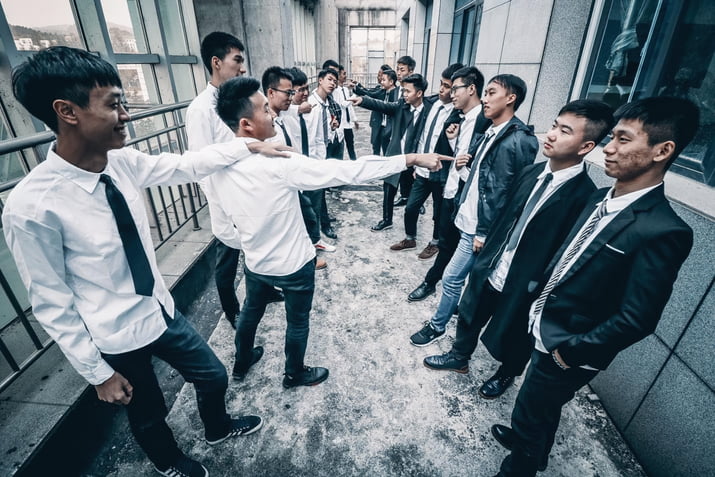 High school students split into two rows of white shirts and blazers, with the two sides arguing