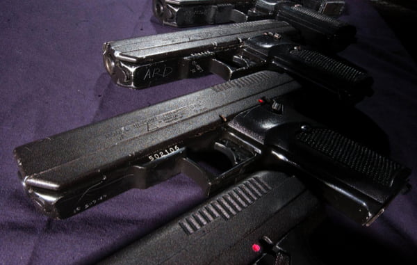 An assortment of Hi-Point pistols is shown on an evidence table, with easily visible serial numbers and personalized markings