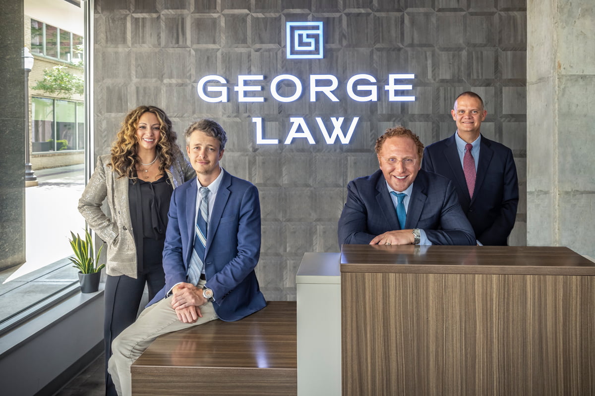 The defense attorneys at George law standing at the front desk of their law firm in Royal Oak