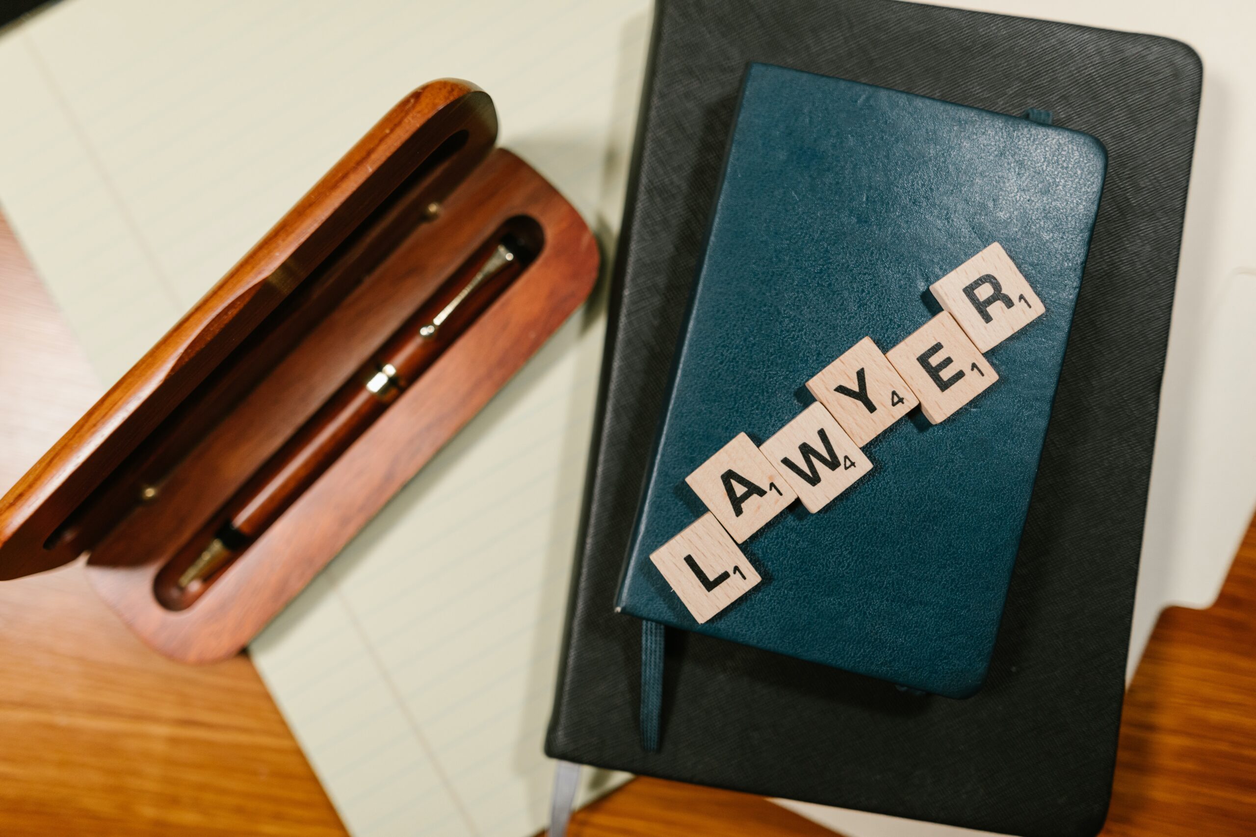 Attorney's desk with pen and the word Lawyer in square blocks.- Criminal defense attorney