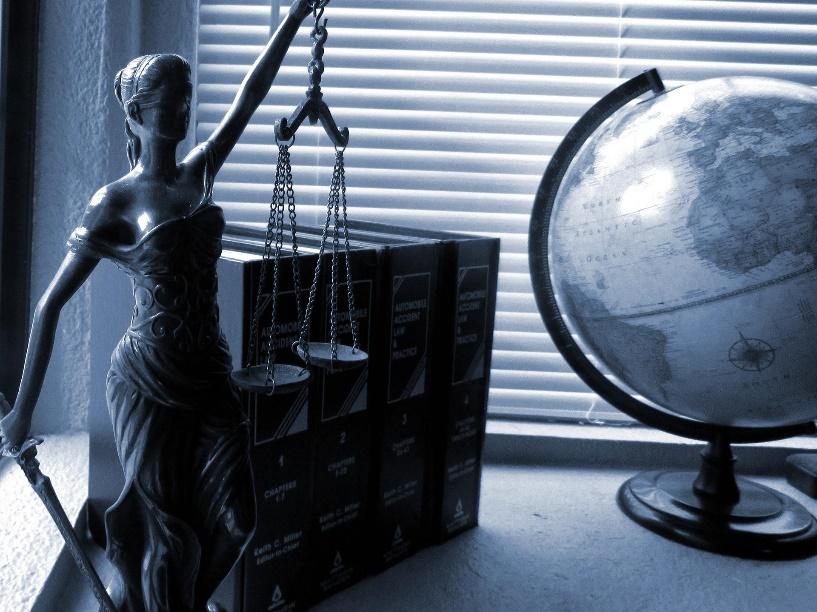 Featured: Lady Justice on desk with globe- Conspiracy Lawyer