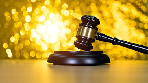 Featured: Judges gavel on wooden desk with bright gold sparkly background- Getting Rid of an Arrest Warrant in Michigan