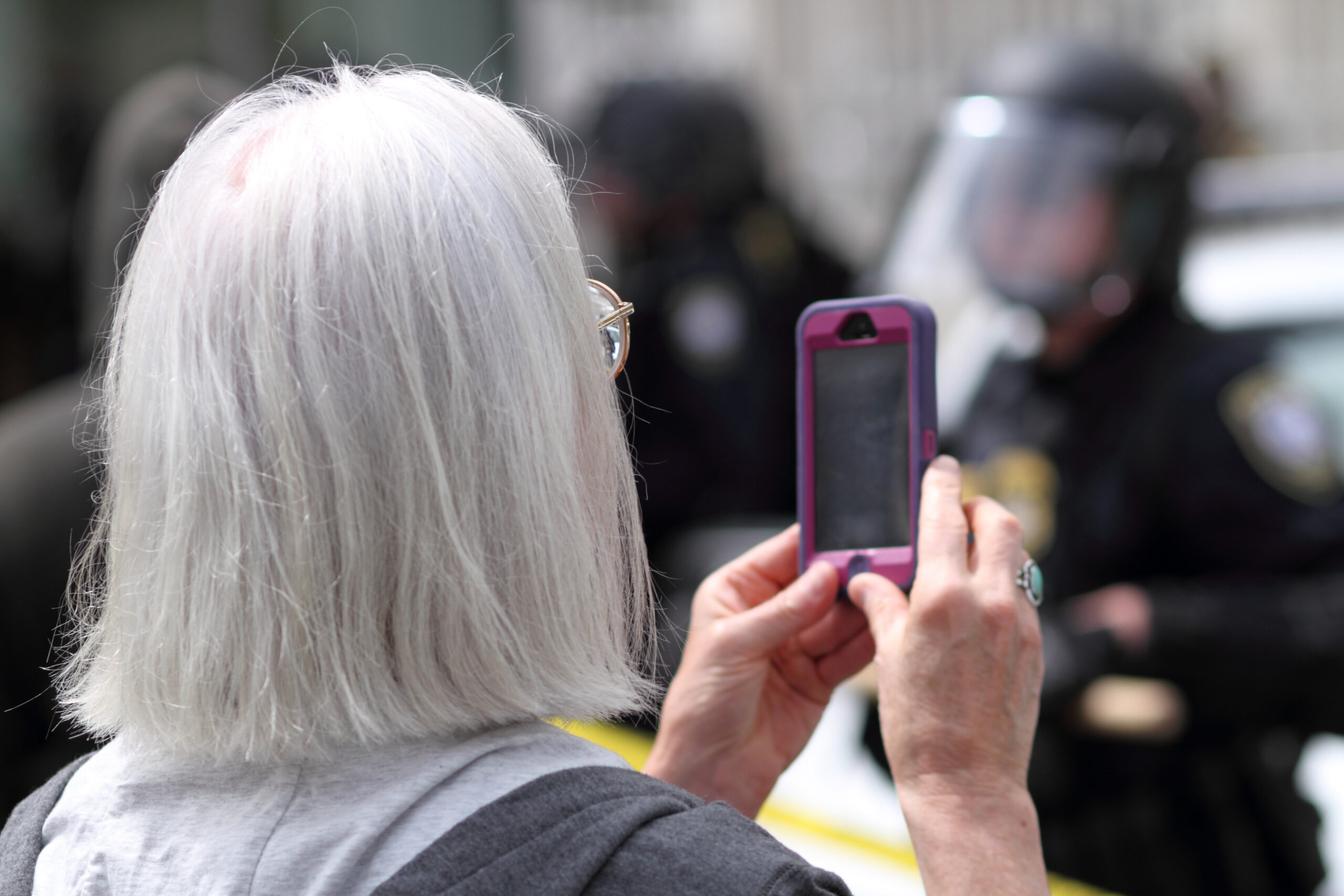 Featured: Female protester recording police officer with cell phone- Right to Record a Police Officer in Michigan