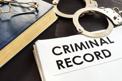 Featured: copy of criminal record, handcuffs, glasses on lawbook - Sealing a juvenile record in Michigan