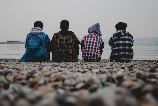 Featured: 4 male juveniles sitting on rocky ledge looking at water- When can juveniles be charged as adults?