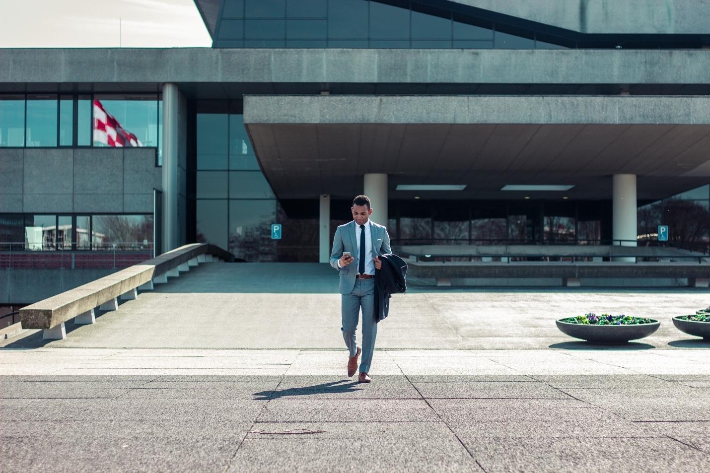 Featured: Male in suit walking out of courthouse texting on phone- Can a Criminal Defense Lawyer Help You Beat a Criminal Sexual Conduct Charge?
