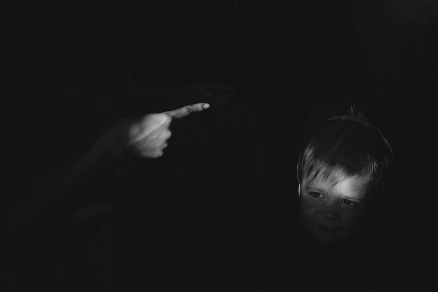 Featured: Finger pointing at child's face who is afraid on black background-- Michigan Child Abuse Criminal Defense Lawyer