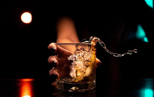 Featured: Female hand holding glass of whiskey with chain - Date Rape Lawyer